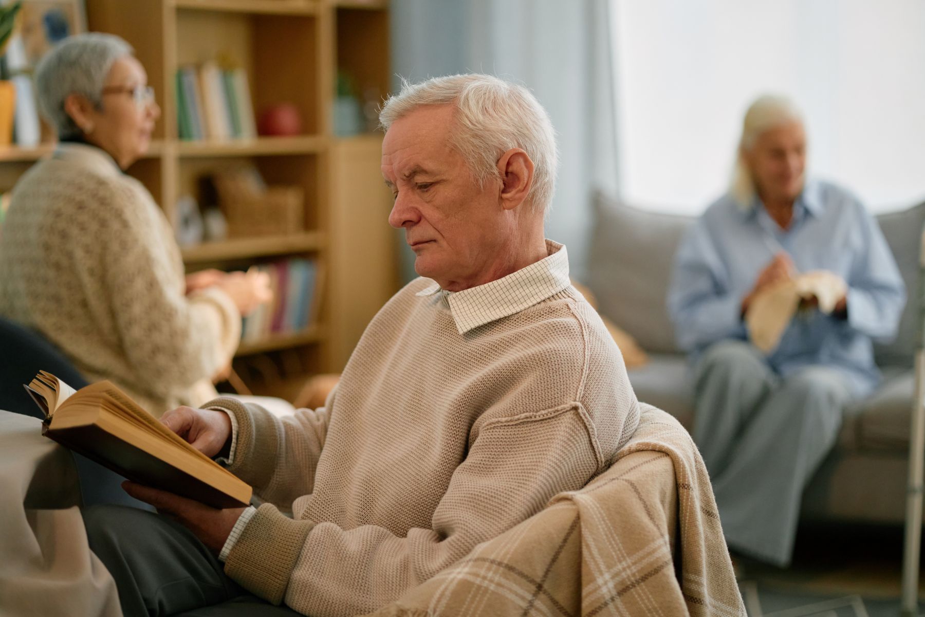 senior man reading book in a comfortable living room