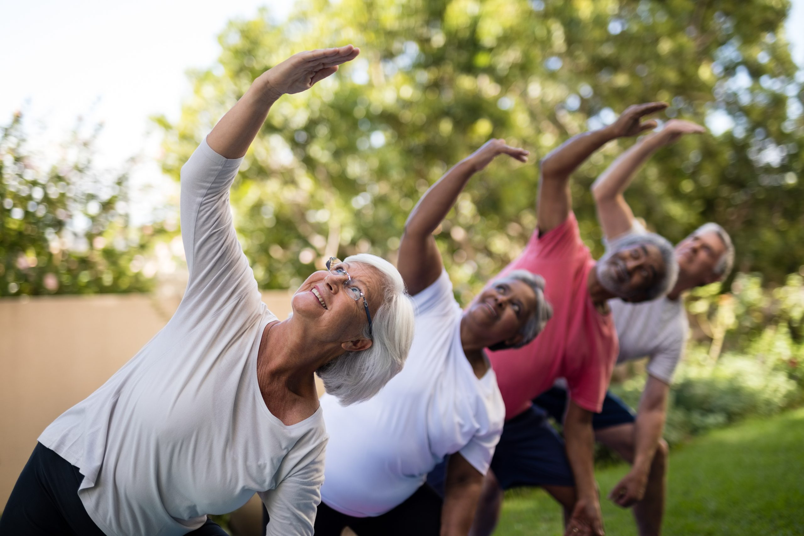 senior living residents doing outdoor yoga senior women doing outdoor yoga as part of a fitness class.